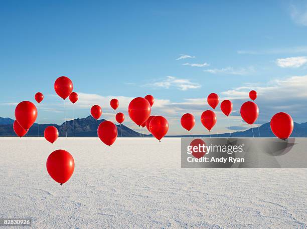 group of red balloons on salt flats. - red balloons stock pictures, royalty-free photos & images