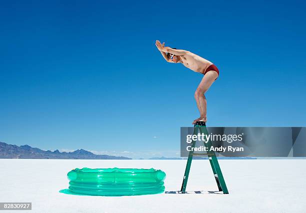 man diving into inflatable pool from ladder. - idiots fotografías e imágenes de stock