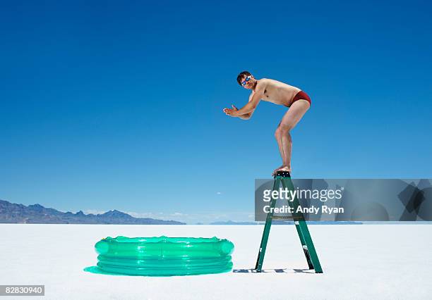 man diving off ladder into inflatable pool. - bent ladder stock pictures, royalty-free photos & images