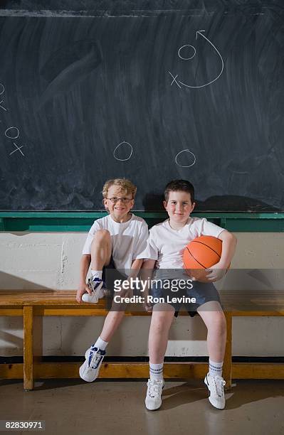 two boys sitting on gym bench, portrait - blackboard qc stock-fotos und bilder
