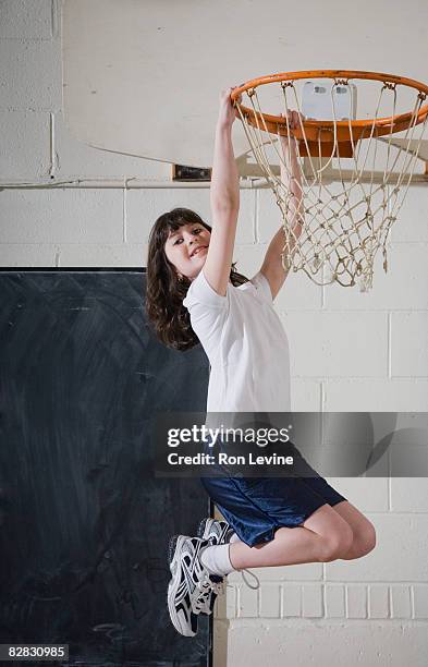 young girl hanging off basketball hoop, portrait - blackboard qc stock-fotos und bilder