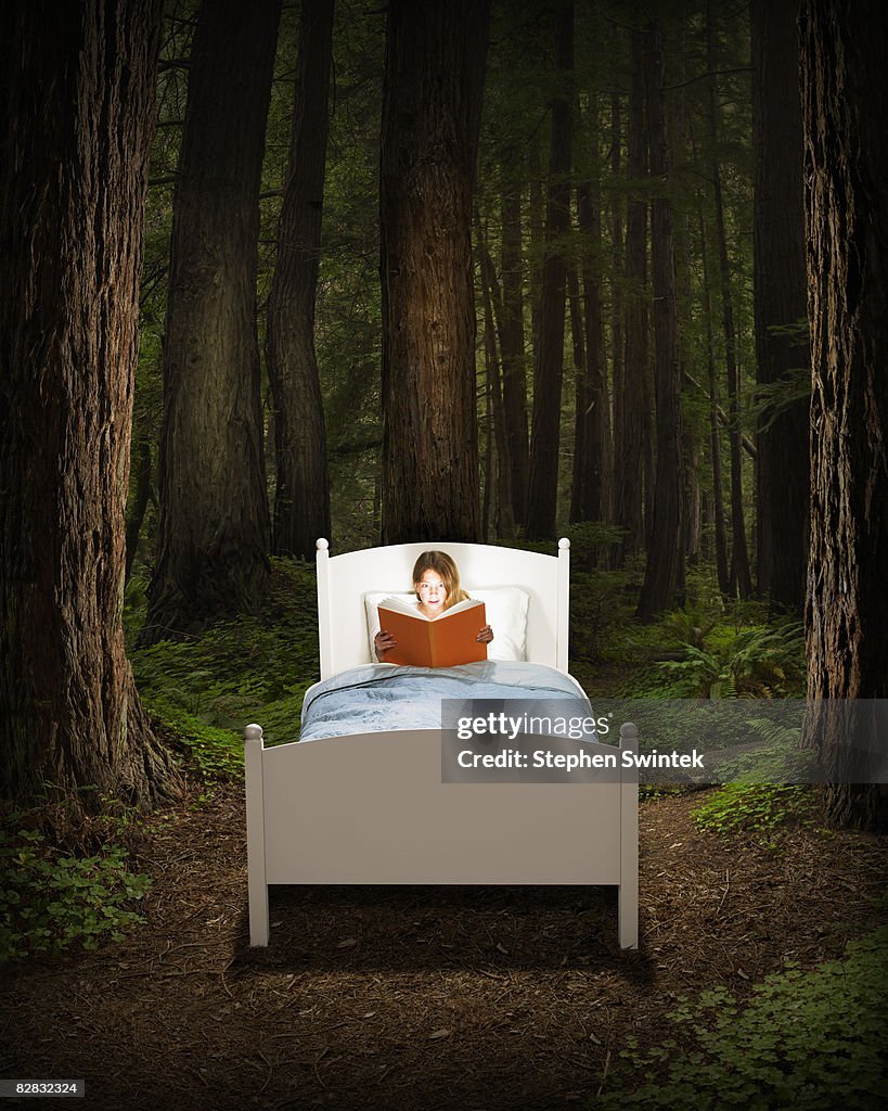 Girl reading book in bed located in a forest