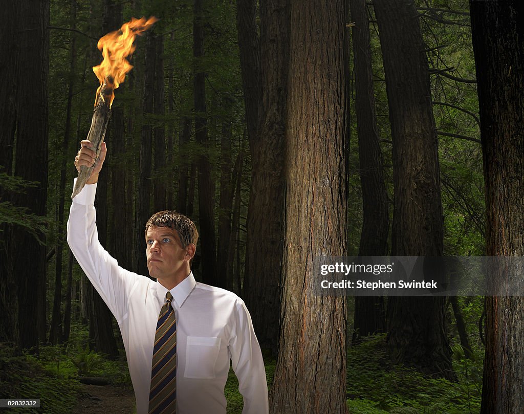 Man holding flaming torch in dark forest