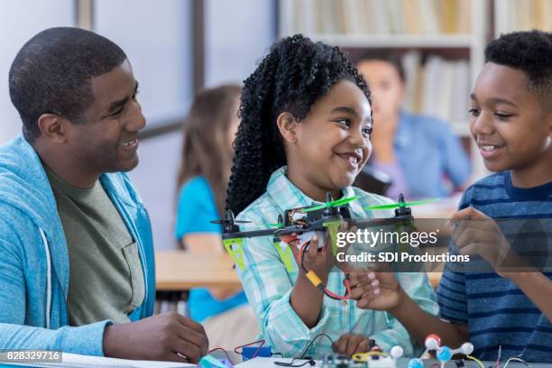 little girl proudly displays completed robot at school for father and brother - father and children volunteering imagens e fotografias de stock