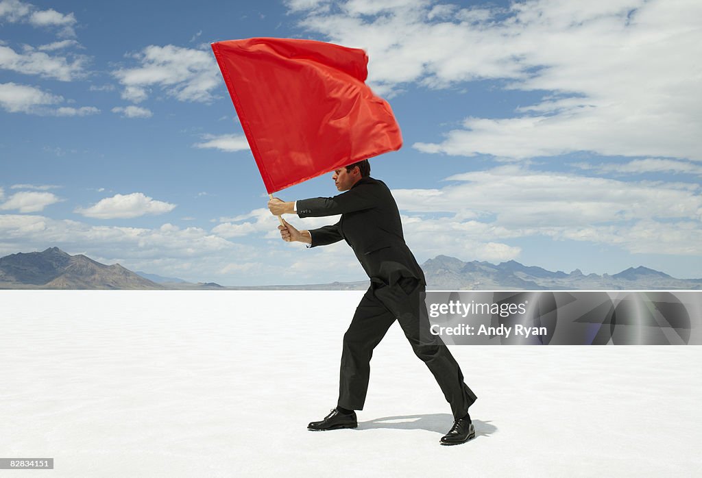 Businessman Waving Red Flag on Salt Flat