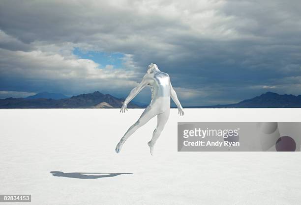 man in silver suit rising upward on salt flat. - gray alien stock pictures, royalty-free photos & images