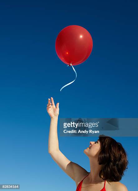 woman releasing red balloon - releasing stock pictures, royalty-free photos & images