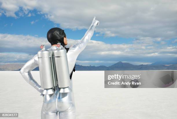 man wearing jet pack pointing to sky. - jet pack stock pictures, royalty-free photos & images