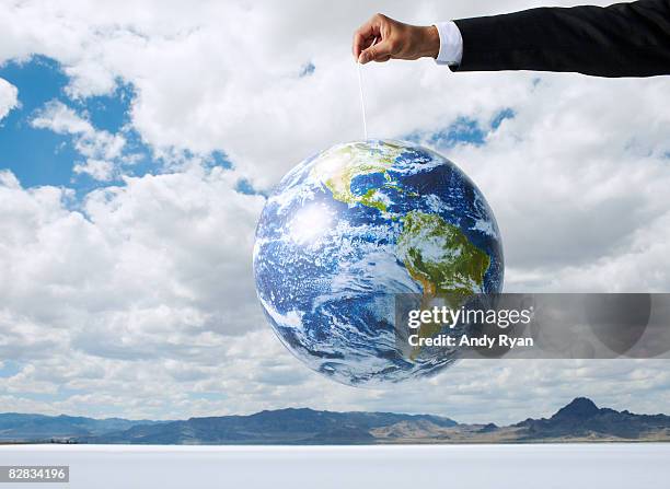 businessman holding globe on a string - global mindset stock pictures, royalty-free photos & images