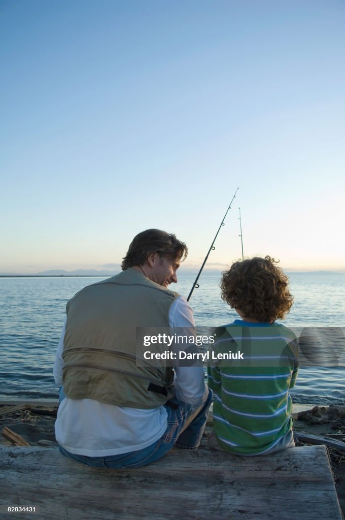 Father and son fishing on beach at sunset