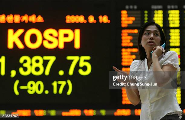 Woman looks at a board showing stock price index at a stock brokerage firm in Seoul September 16, 2008 in Seoul, South Korea. The Korean stock...