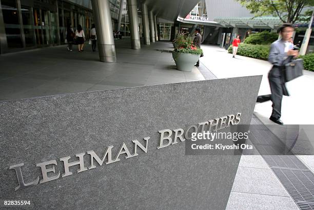Man walks past the sign of Lehman Brothers Holdings at the Tokyo branch of Lehman Brothers Holdings on September 16, 2008 in Tokyo, Japan. The...