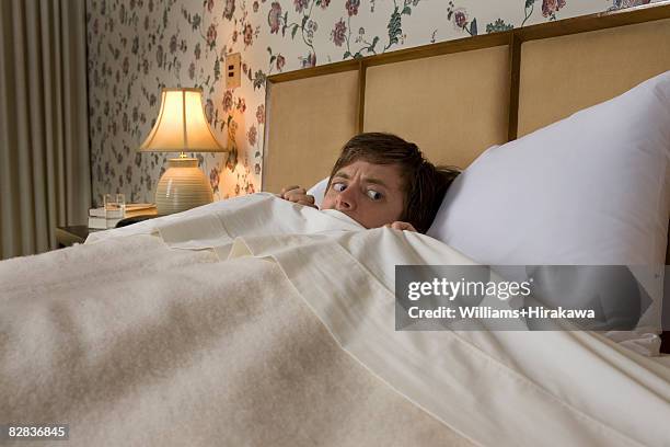 man in bed with nervous look - fear foto e immagini stock