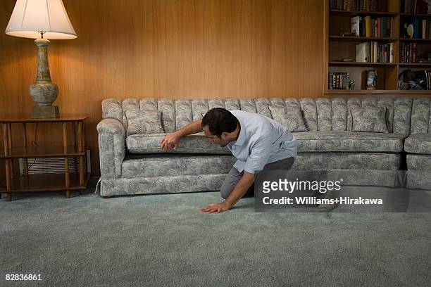man looking under sofa cushion - zoeken stockfoto's en -beelden