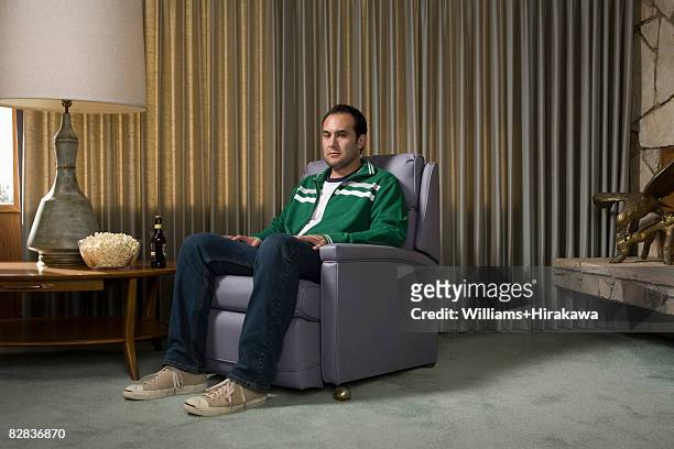 man in chair watching television - sit in stockfoto's en -beelden