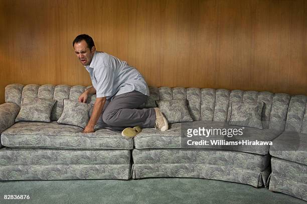 man on sofa looking scared - omlaag kijken stockfoto's en -beelden