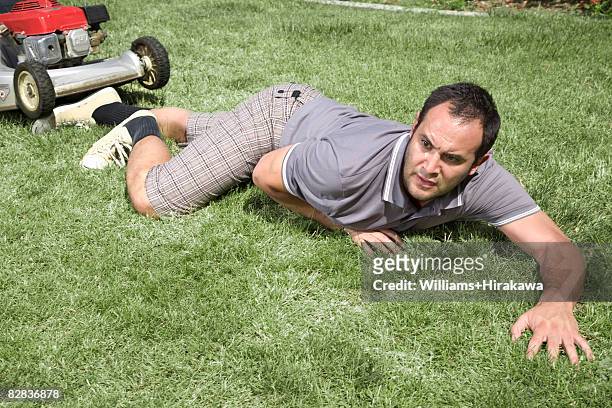 fallen man in front of lawnmower - china foto e immagini stock