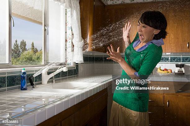 woman being sprayed by water from kitchen sink - water sprayer stock pictures, royalty-free photos & images