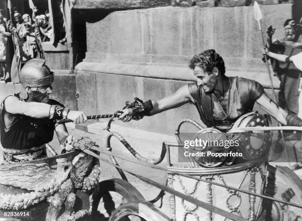 Judah Ben-Hur, played by American actor Charlton Heston struggles with Messala, played by Stephen Boyd during the chariot race from the film, 'Ben...