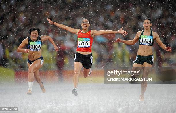 Sanaa Benhama of Morocco celebrates in the rain next to second place Ilse Hayes of South Africa and Maryna Chyshko of the Ukraine after winning the...