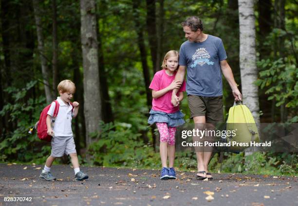 Stay at home dad Peter Hubbard walks with his children Iris center, and Park after they were dropped off from the bus after school Friday, September...