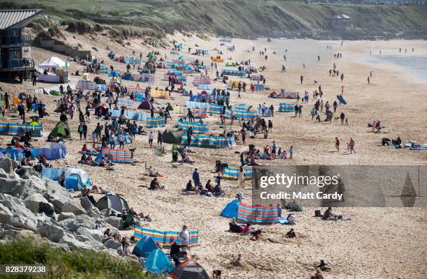 People gather on Fistral beach as surfers compete in a heat of the World Surf League Boardmasters Quicksilver Open at the annual Boardmasters...