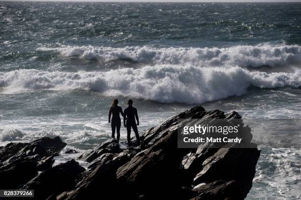 People watch the waves break on Fistral beach as surfers compete in a heat of the World Surf League Boardmasters Quicksilver Open at the annual...