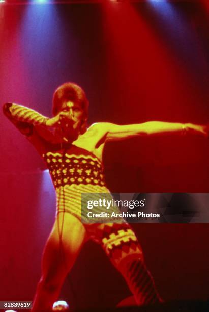 British singer David Bowie performs onstage wearing makeup and a costume that covers only one leg and one arm, 1973.