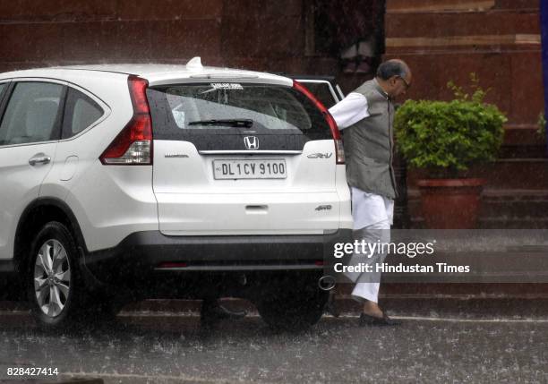 Senior Congress leader Digvijaya Singh running to cover himself during the sudden rain at the Parliament during the Monsoon Session on August 9, 2017...