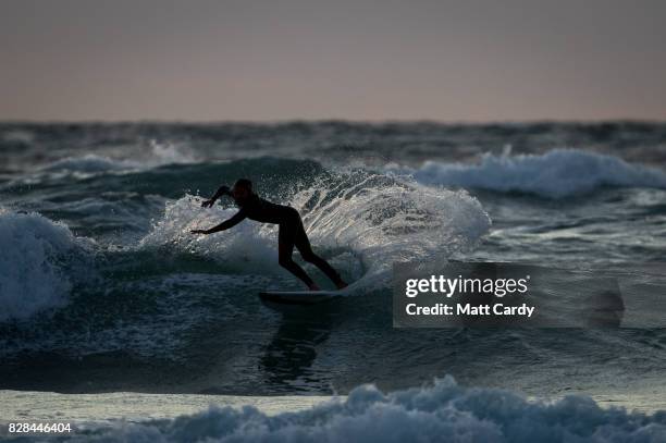 Surfer catches a wave as the sun sets at the end of the first day of the annual Boardmasters festival held on Fistral beach in Newquay on August 9,...