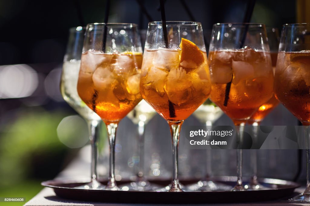 Many glasses with orange cocktails, black background