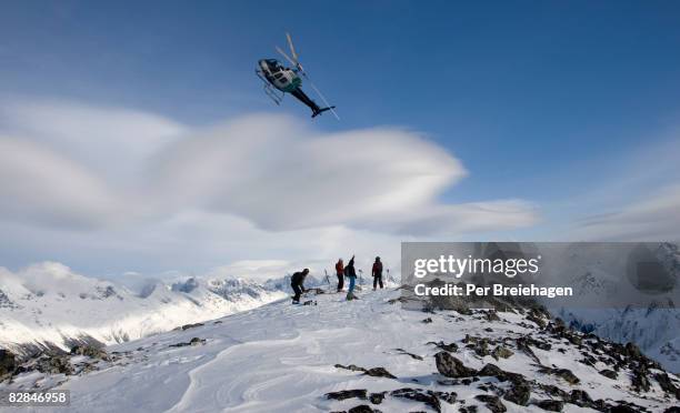 helicopter flies of skiers on mountain top - heli skiing stock pictures, royalty-free photos & images