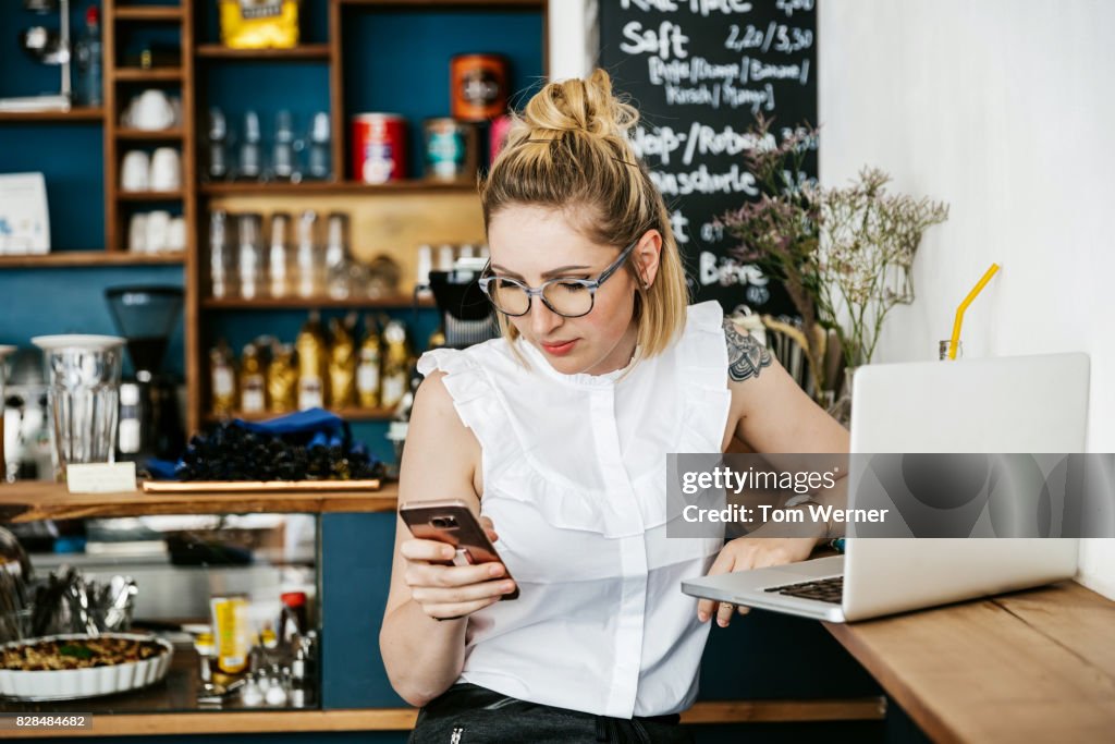 Stylish Young Woman Using Smartphone While Working At Cafe
