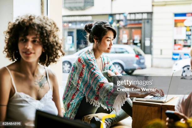 young group of people working and socialising in cafe - depth of field imagens e fotografias de stock