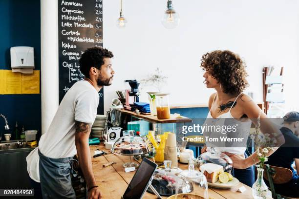 waiter taking order from young customer at cafe counter - baloch culture stock pictures, royalty-free photos & images