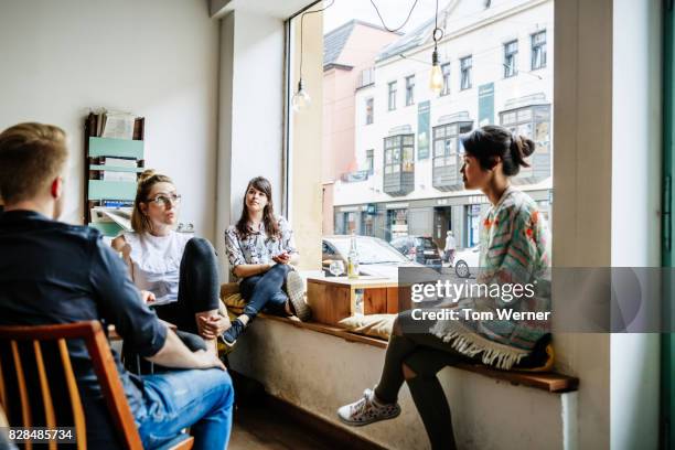 group of friends chatting and relaxing together in cafe - sprechen zusammen cafe stock-fotos und bilder