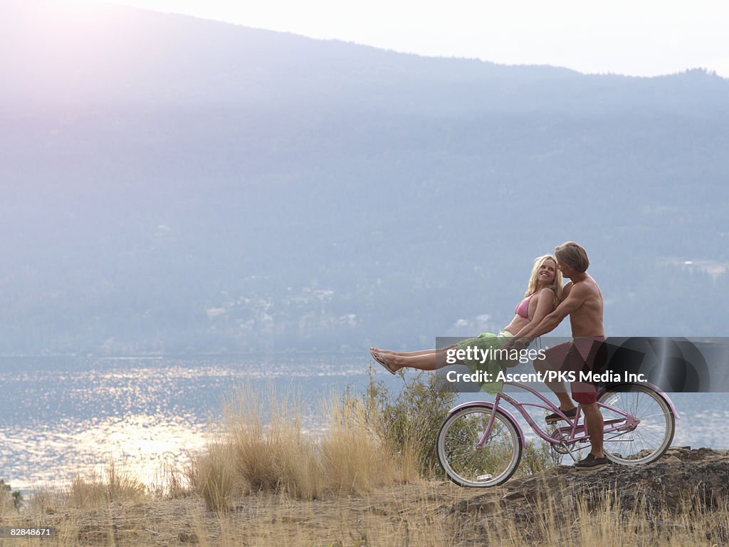 Couple on cruiser bike on rocky path above lake