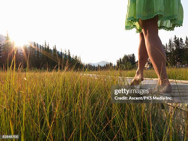 woman walking along edge of boardwalk, low view - legs walking stock-fotos und bilder