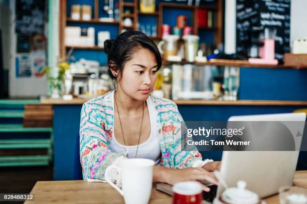 Young Woman Working On Laptop In Colourful Coffee Shop