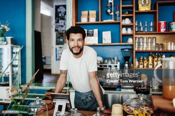 young barista smiling leaning on coffee shop counter - one mid adult man only bildbanksfoton och bilder