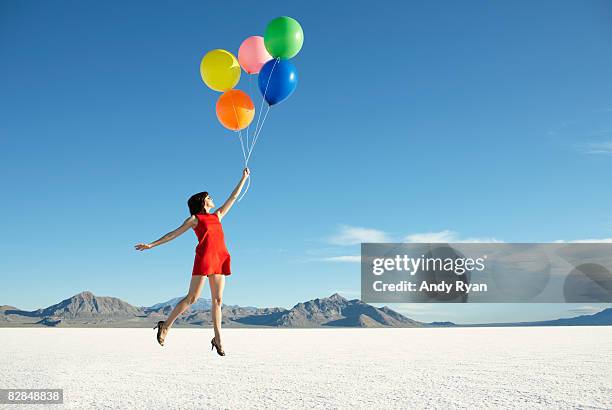 balloons carrying off young woman - woman flying stock pictures, royalty-free photos & images