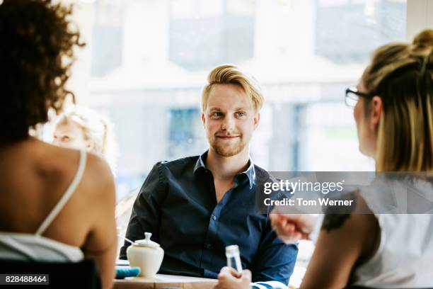 man smiling as he talks with friends in cafe - flirter photos et images de collection