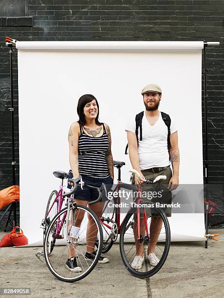 couple standing on sidewalk holding bikes - kulisse stock-fotos und bilder