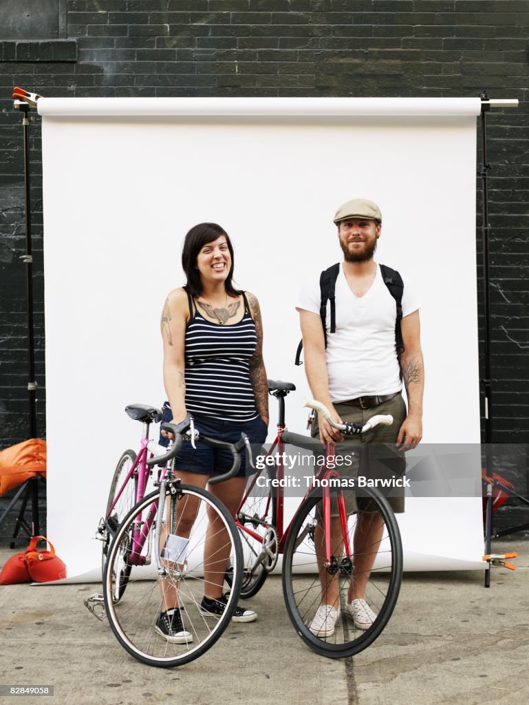 Couple standing on sidewalk holding bikes