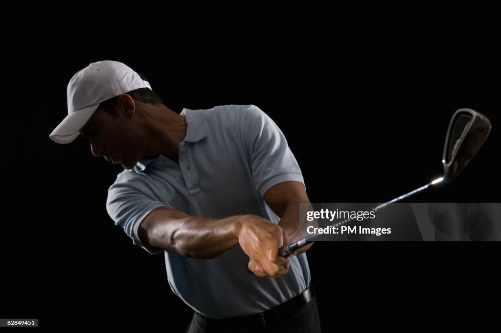 Young man swinging golf club