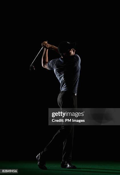 young man swinging golf club - golfschwung stock-fotos und bilder
