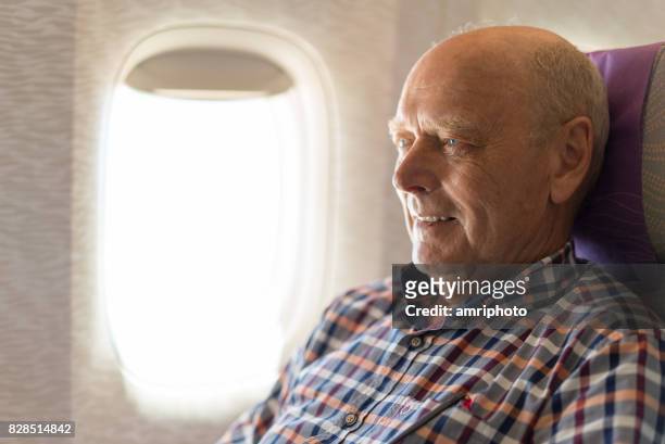 senioren nemen op de wereld, 72 jaar oude mens in vliegtuig op raam glimlachen - window seat stockfoto's en -beelden