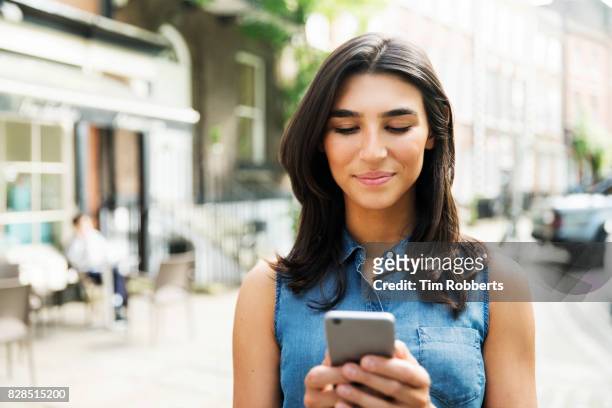 woman using smart phone near cafe - sleeveless top stock pictures, royalty-free photos & images
