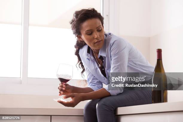 woman relaxing after work by drinking wine in the kitchen. - alcohol abuse stock pictures, royalty-free photos & images