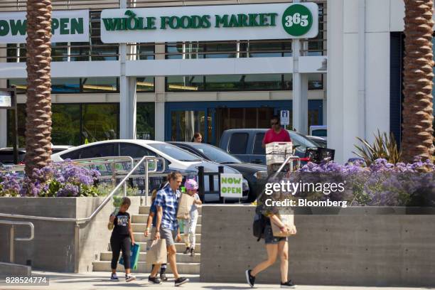 Customers carry shopping bags outside of a Whole Foods Market 365 location during the grand opening in Santa Monica, California, U.S., on Wednesday,...